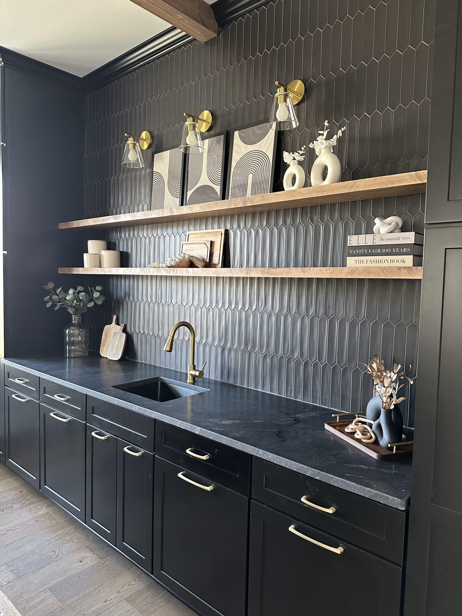 A kitchen with black cabinets and shelves in it