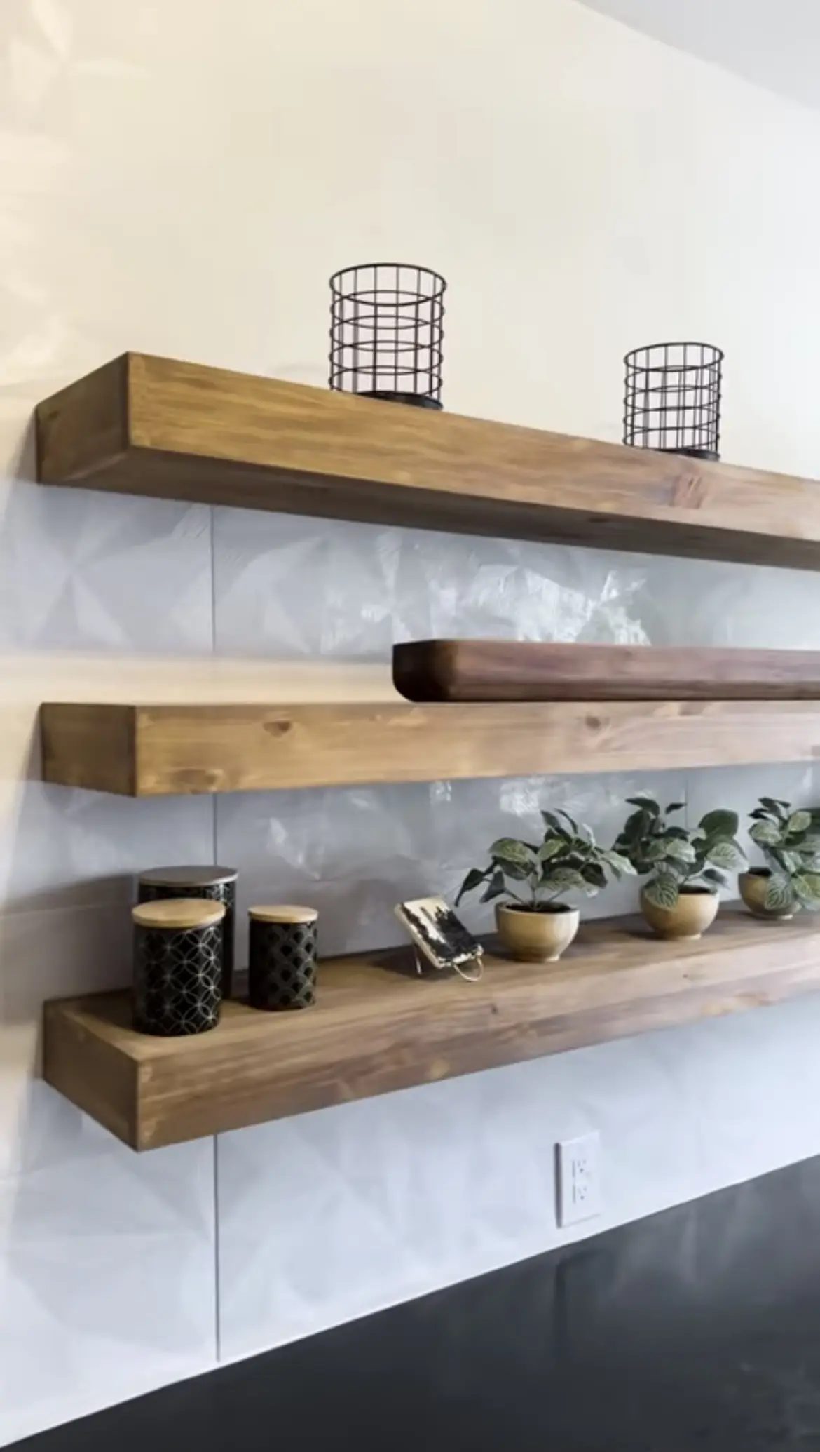 A set of three wooden shelves with plants on them.