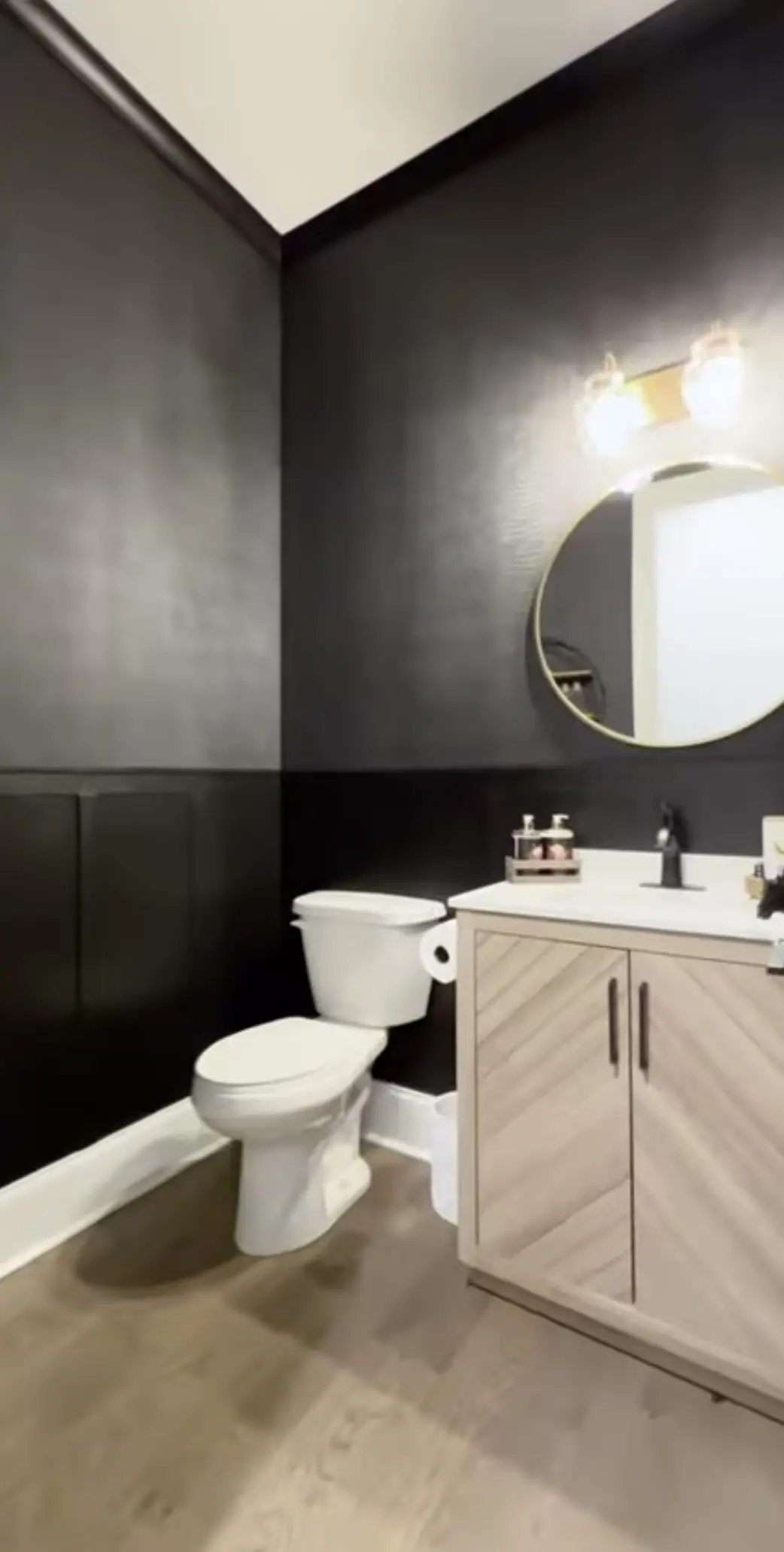 A bathroom with black walls and white fixtures.