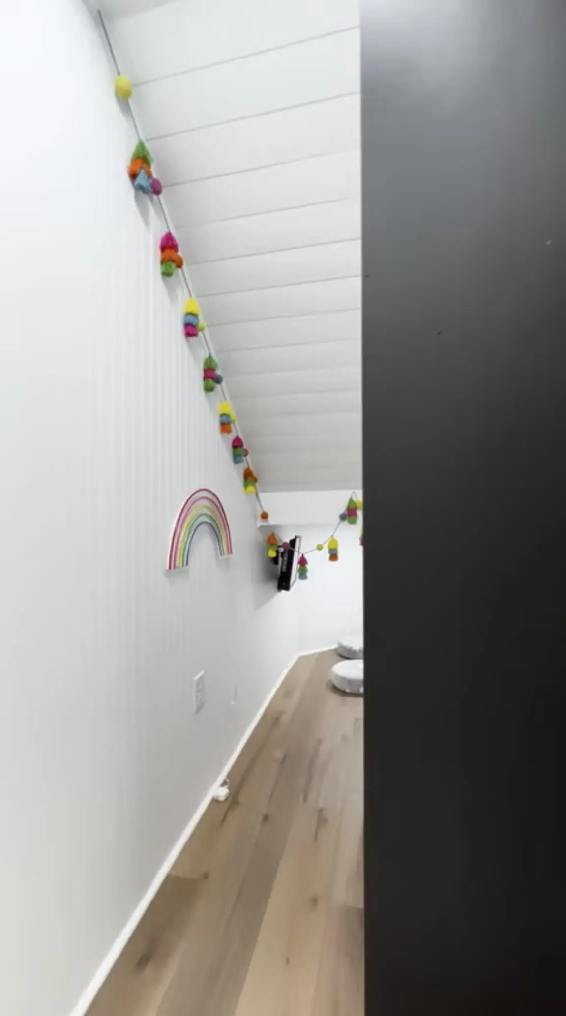 A hallway with a rainbow and a bunch of little flowers hanging from the wall.