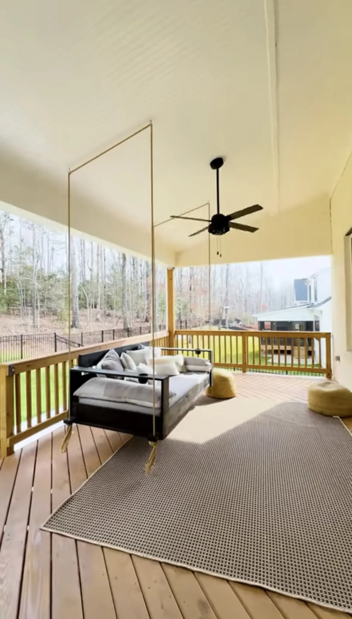 A porch with a swing bed and table in it