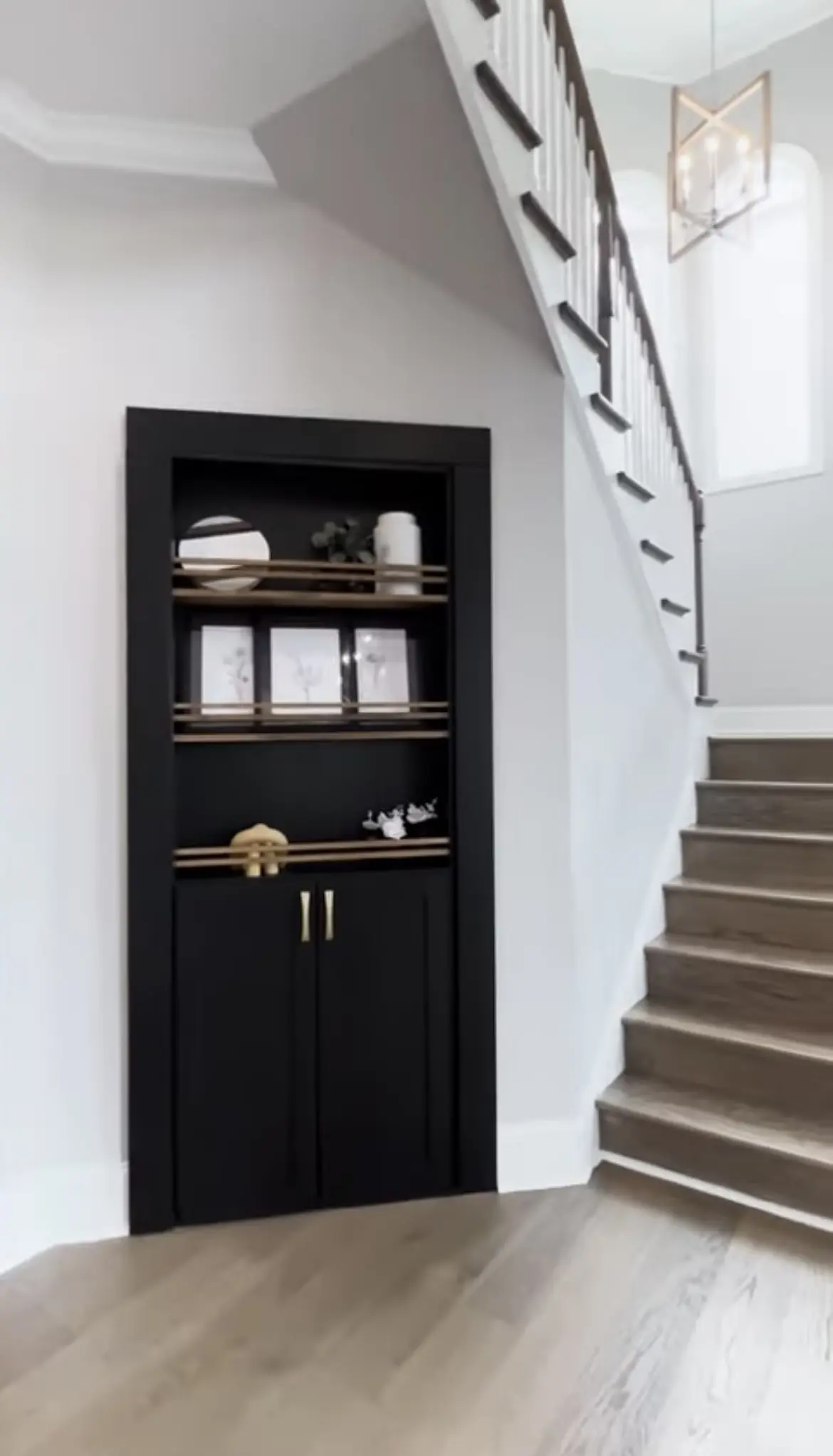 A black cabinet with gold handles and shelves.