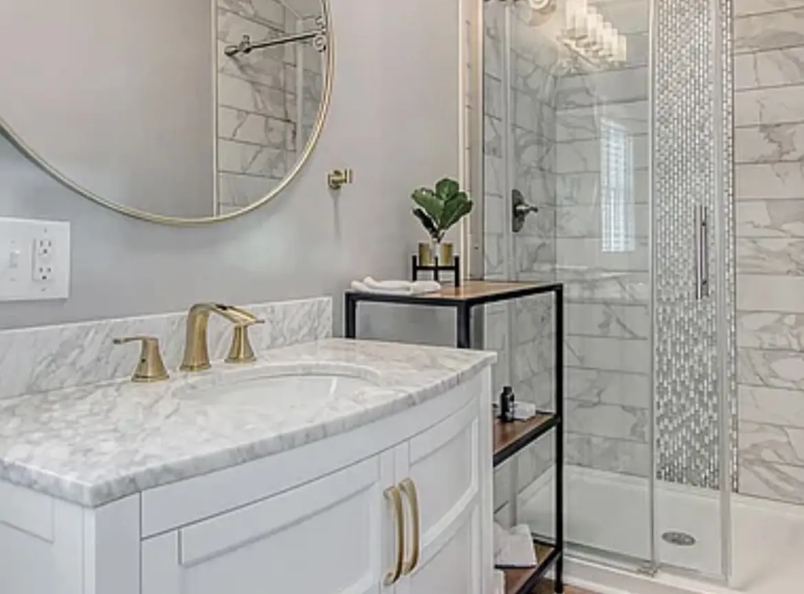 A bathroom with marble walls and floors, a large mirror over the sink.