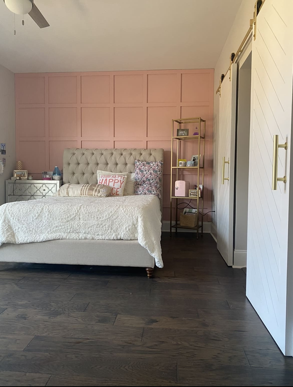 A bedroom with pink walls and white furniture.