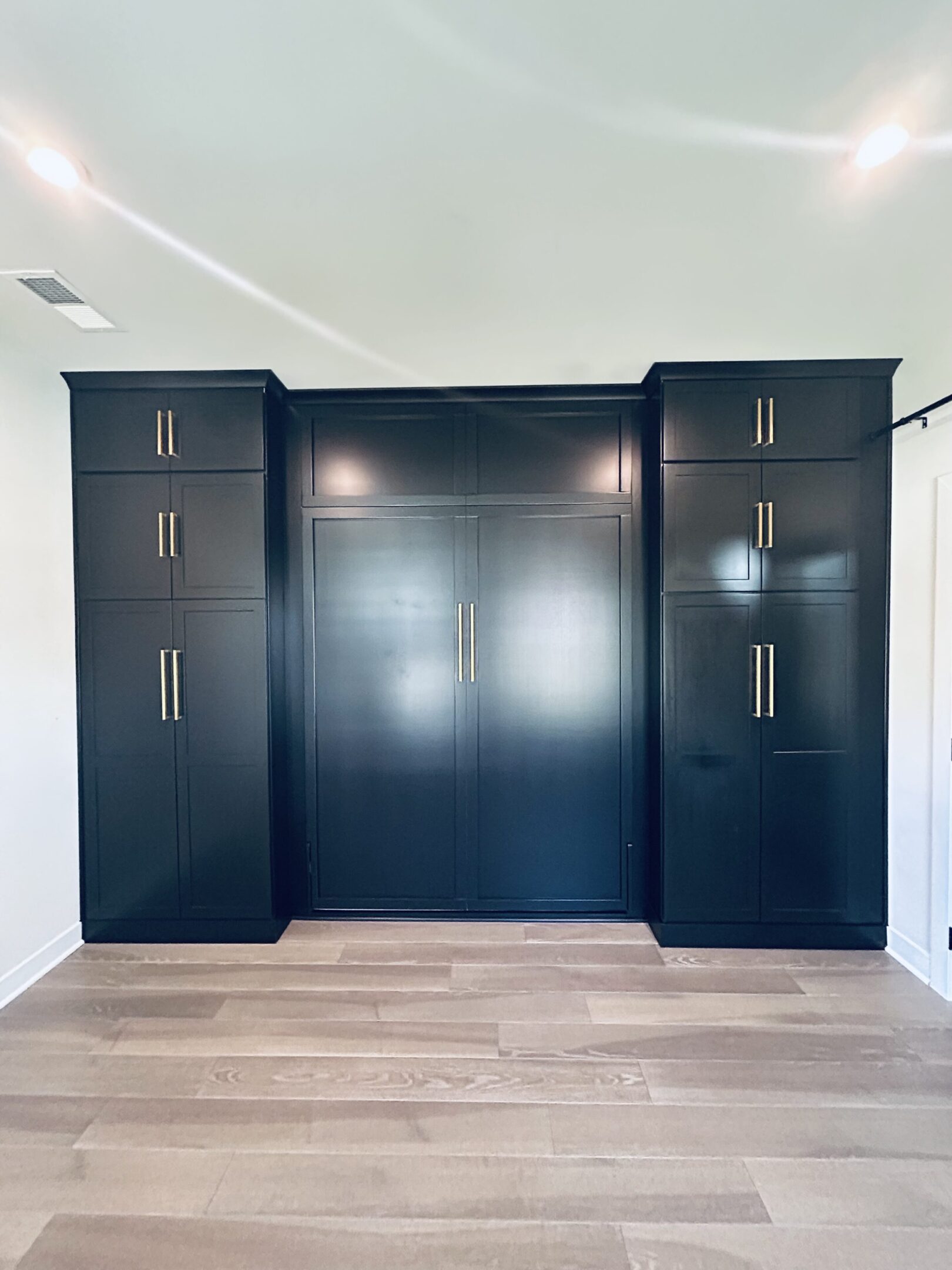 A black cabinet with chrome handles in the middle of it.